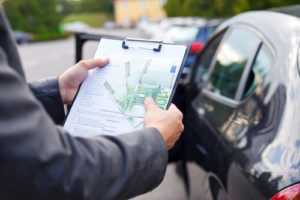 Ein Mann auf einem Parkplatz hält ein Klemmbrett mit einem Vertrag und Bargeld