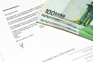 Ein paar hundert Euro Scheine liegen auf einem Kreditvertrag
