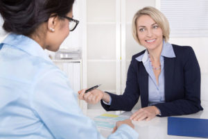 Zwei Frauen in Businesskleidung beratschlagen an einem Schreibtisch