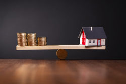 Gewinnspanne der Banken bei Hypothekenkrediten Modellhaus und Geldstapel auf Waage