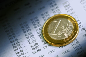 Deutschland baut Schulden ab Eine Ein-Euro Münze auf einem Blatt mit vielen monatlichen Zahlen