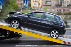 Ein dunkler Kleinwagen wird auf einen Abschleppwagen geladen