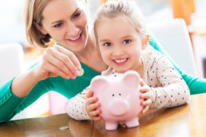 Eine Mutter und ihre kleine Tochter füttern ein Sparschwein