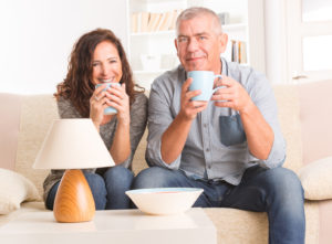 Ein Paar mittleren Alters sitzt auf der Couch und trinkt Kaffee