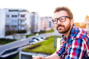 Ein junger Gründer mit Brille und Bart blickt in die Ferne