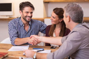 Ein glückliches Paar bedankt sich beim Finanzberater per Handschlag