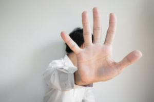 Ein Mann streckt abwehrend sine Hand vor und wendet das Gesicht ab