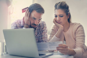 Ein besorgtes Paar studiert das Kleingedruckte eines Vertrags und nutzt einen Laptop