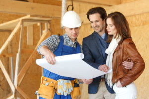 Auf der Baustelle lässt sich ein Paar von einem Handwerker den Bauplan erklären