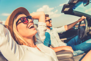 Ein junges Paar ist froh und entspannt im offenen Cabrio unterwegs