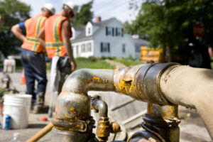 Zwei Bauarbeiter pumpen mit großen Schläuchen Wasser ab