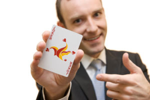 Ein Mann im Anzug streckt eine Joker Spielkarte vor